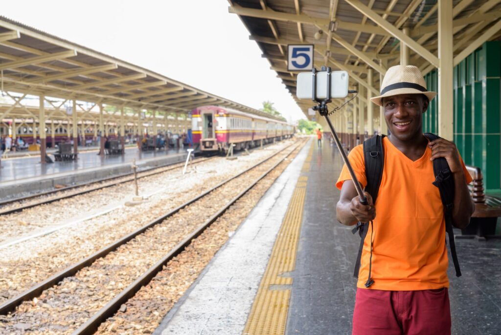 Young happy black African tourist man smiling and taking selfie